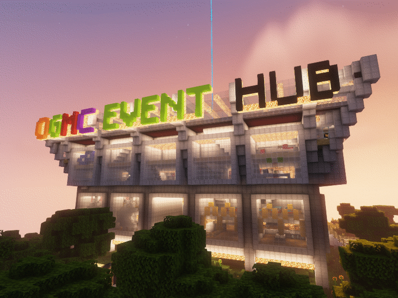 A large metal and glass stadium building with shops inside it and an illuminated sign saying OGMC EVENT HUB